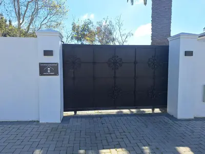 a black fence with two white gates in a driveway at Cape Dutch haven in Durbanville