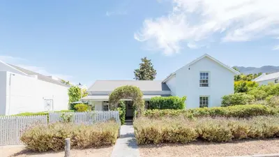 a white house with a fence in front of it at Waymaker Cottage in Franschhoek