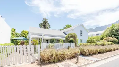 a white fence in front of a white house at Waymaker Cottage in Franschhoek