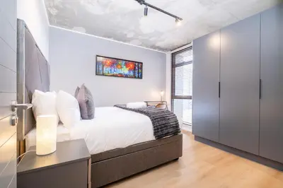 a bedroom with white walls and a bed with white pillows at 317 Riverlands - Lux 1 bedroom Apartment in Cape Town