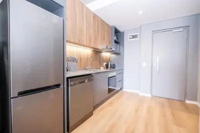 a kitchen with a stainless steel refrigerator and wooden cabinets at 317 Riverlands - Lux 1 bedroom Apartment in Cape Town