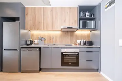 a kitchen with stainless steel appliances and wooden cabinets at 317 Riverlands - Lux 1 bedroom Apartment in Cape Town