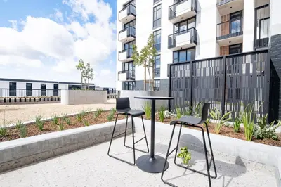 a table and two chairs in front of a building at 318 Riverlands - Lux 1 bedroom Apartment in Cape Town