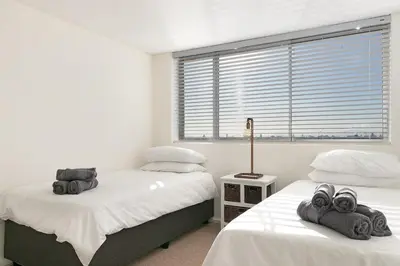 a bedroom with two beds and a window with blinds at Dolphin Beach C111 Sea -Table Mountain Views at Dolphin Beach in Cape Town