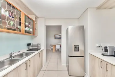 a kitchen with a refrigerator and a table at Beautiful & Modern Dolphin Beach CG12 by HMH in Cape Town