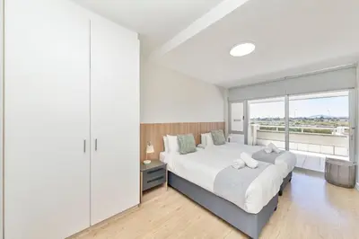 a bedroom with a large bed and a large window at Beautiful & Modern Dolphin Beach CG12 by HMH in Cape Town