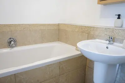 a bathroom with a bath tub and a sink at Modern 1BR Flat - Near Canal Walk in Cape Town