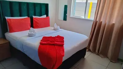 a bed with red pillows and a red blanket on it at Neo & Ruks excellent Rooms in Goodwood
