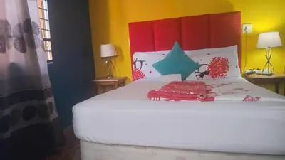 a bedroom with a white bed with a red headboard at Neo & Ruks excellent Rooms in Goodwood