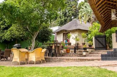a patio with chairs and a table in front of a house at Winelands Villa Guesthouse and Cottages in Somerset West
