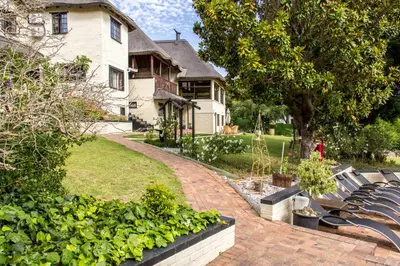 a group of benches in a yard with a house at Winelands Villa Guesthouse and Cottages in Somerset West