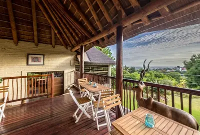 a porch with a table and chairs on a deck at Winelands Villa Guesthouse and Cottages in Somerset West