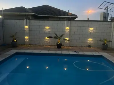 a blue swimming pool with lights on a house at Sunbird Poolhouse in Silver Sands