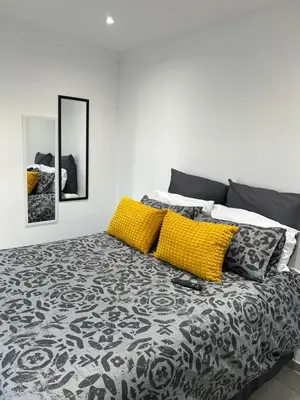 a bedroom with a bed with yellow and black pillows at Sunbird Poolhouse in Silver Sands