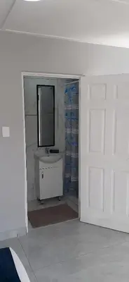 a white bathroom with a sink and a mirror at RoomIsGood in Cape Town