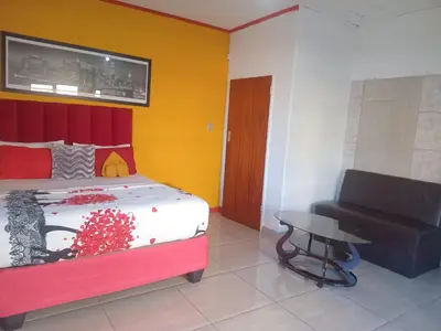 a bedroom with a bed and a chair and a table at Neo & Ruks Rooms Parow 5 in Goodwood