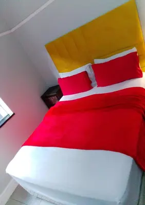 a bedroom with a red and white bed with red pillows at Neo & Ruks Rooms Parow 5 in Goodwood