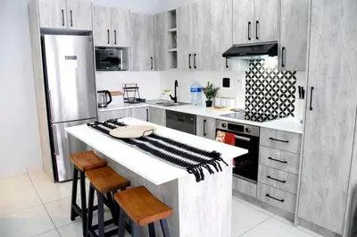 a kitchen with a white counter top and wooden cabinets at Modern Stylish Home In Cape Town in Cape Town