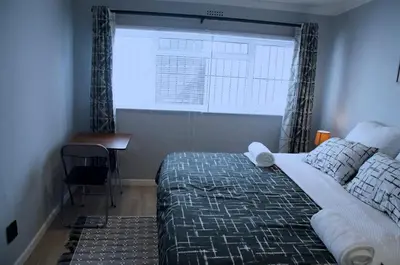 a bedroom with a bed and a window and a desk at Modern Stylish Home In Cape Town in Cape Town
