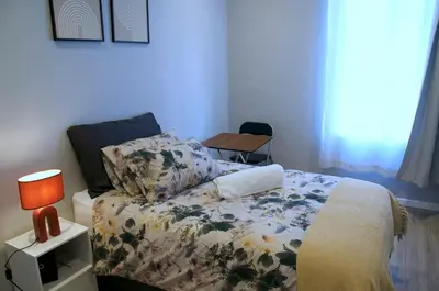 a bedroom with a bed and a lamp and a table at Modern Stylish Home In Cape Town in Cape Town
