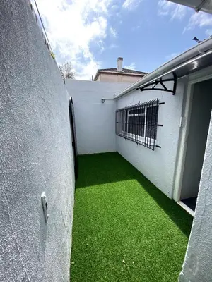 a courtyard with green grass next to a white wall at Modern Stylish Home In Cape Town in Cape Town