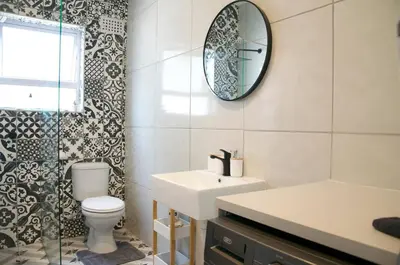a bathroom with a toilet and a sink and a mirror at Modern Stylish Home In Cape Town in Cape Town