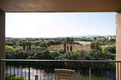 a balcony with a chair and a view of a river at Family Suite-Two Bedroom Waters Edge in Cape Town