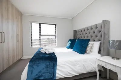 a bedroom with a large bed with blue pillows at Family Suite-Two Bedroom Waters Edge in Cape Town