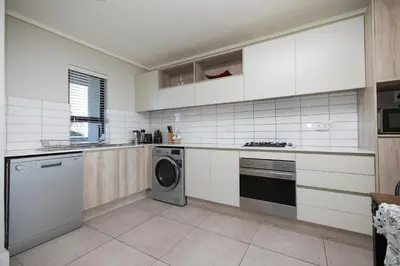a kitchen with white cabinets and a washer and dryer at Family Suite-Two Bedroom Waters Edge in Cape Town