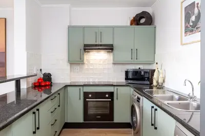a kitchen with green cabinets and a sink at Luxurious Palm View Apartment Cape Town in Cape Town