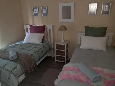 a bedroom with two beds and a lamp on a table at Deo Volente Self-Catering Cottage in Kuilsrivier