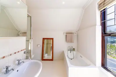 a bathroom with two sinks and a tub and a window at Franschhoek Charm in Franschhoek