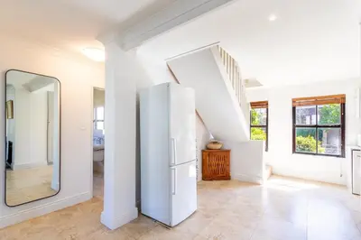 a white hallway with a mirror and a refrigerator at Franschhoek Charm in Franschhoek