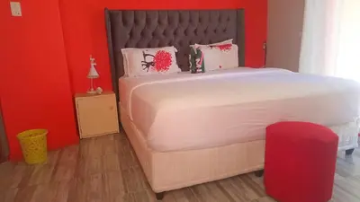 a bedroom with a large bed with a red wall at Parow Neo & Ruks Rooms 9 in Avondale