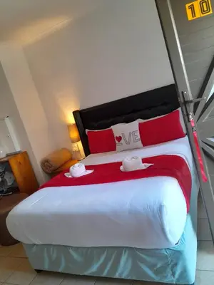 a bedroom with a large bed with red and white pillows at Parow Neo & Ruks Rooms 9 in Avondale