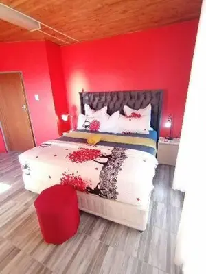 a bedroom with a bed with a red wall at Parow Neo & Ruks Rooms 9 in Avondale