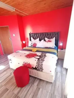 a bedroom with a bed with a red wall at Parow Neo & Ruks Rooms 9 in Avondale