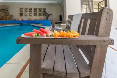 a plate of fruit on a bench next to a swimming pool at TwinPalace in Plattekloof