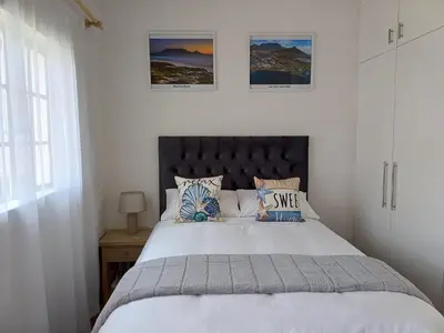 a bedroom with a large white bed with pillows at Cozy Cove in Cape Town