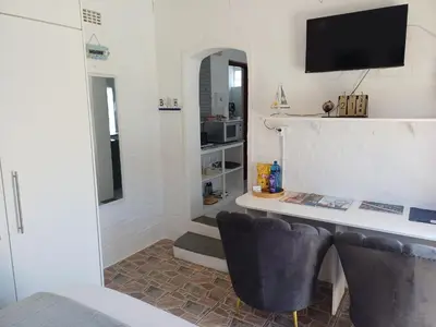 a room with a desk with a television and two chairs at Cozy Cove in Cape Town