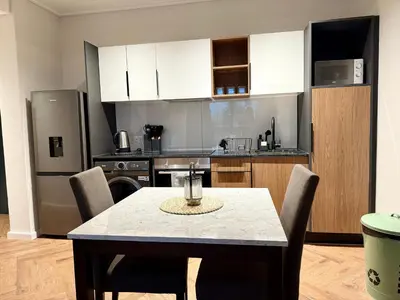a kitchen with a table with chairs and a refrigerator at Luxe 1br apartment on Park in Cape Town