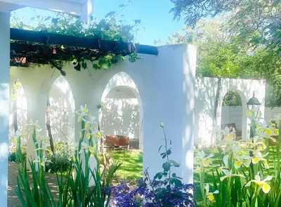 a garden with flowers and a white fence at Bahlaloga Studio Durbanville in Durbanville