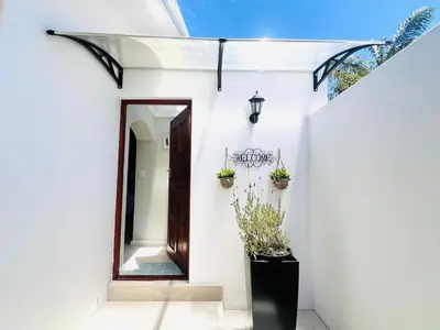 a white house with a door and potted plants at Bahlaloga Studio Durbanville in Durbanville