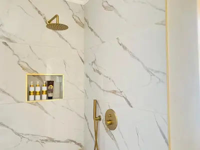 a bathroom with a shower with white marble walls at Bahlaloga Studio Durbanville in Durbanville