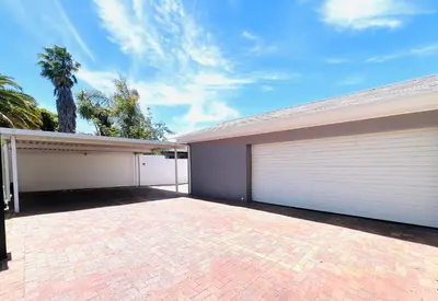 a house with two garage doors and a palm tree at Bahlaloga Studio Durbanville in Durbanville