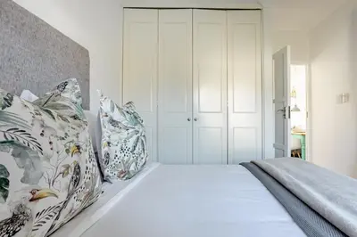 a bedroom with a white bed with floral pillows at Tram View Hideaway in Franschhoek