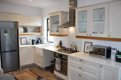 a kitchen with white cabinets and a sink and a microwave at Tram View Hideaway in Franschhoek