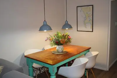 a dining room table with a vase of flowers on it at Tram View Hideaway in Franschhoek