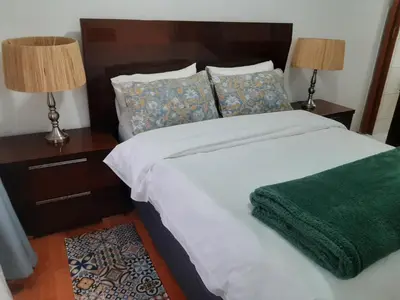 a bed with two lamps and a green blanket on it at Local & Comfortable in Mandalay