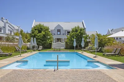 a pool with chairs and umbrellas in front of a building at Winelands Golf Lodges 34 at De Zalze in Cape Town